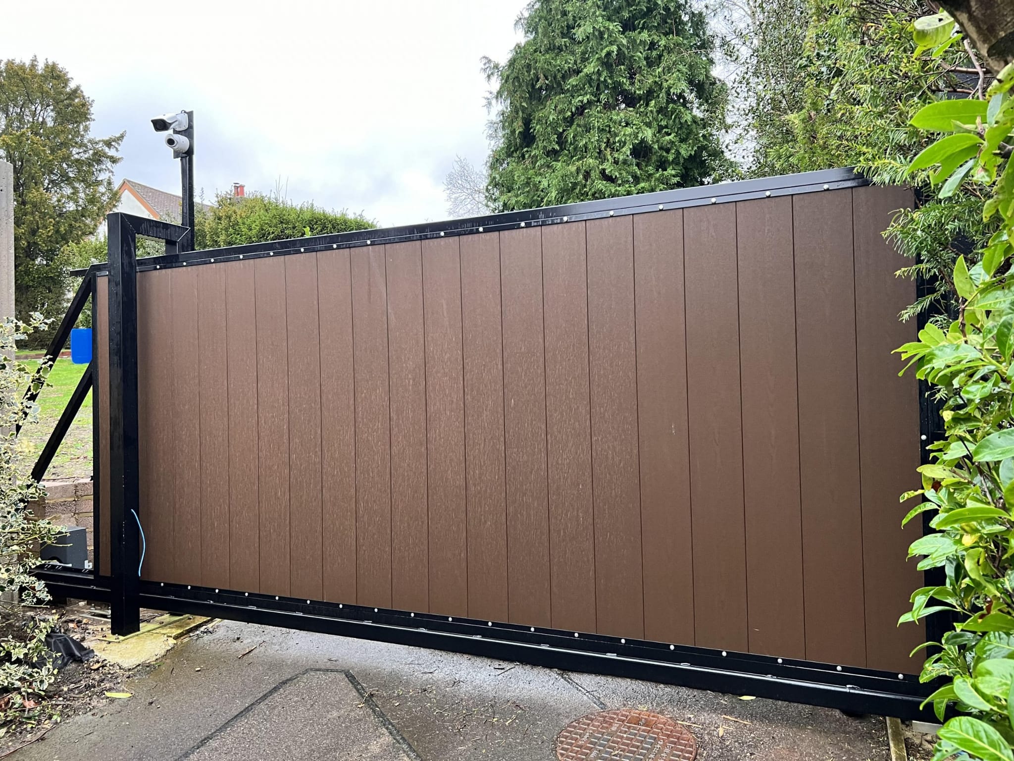 Oak effect sliding composite gate installed on a driveway